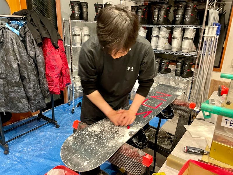 Brushing a rental snowboard by hand